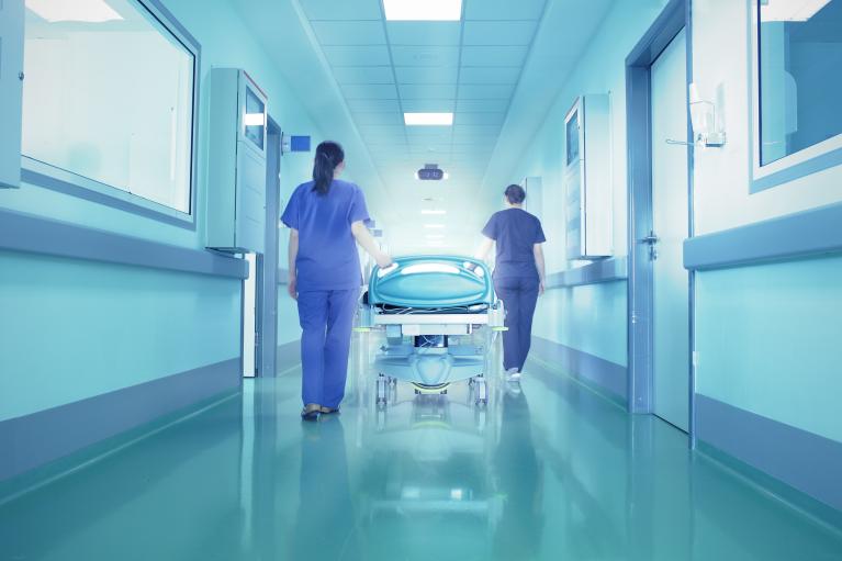 Nurses Walking Bed through Hospital Hallway