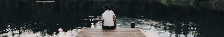 Man sitting on lake dock